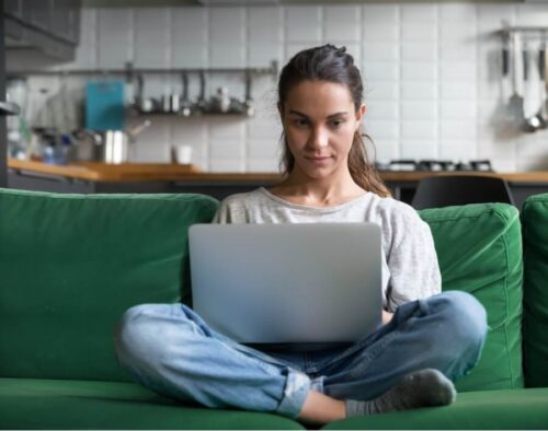 woman sitting on sofa doing online fiction workshop